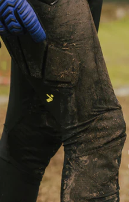 Muddy pants with a brand logo on a blurred outdoor background